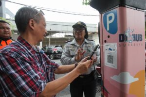 Petugas memantau pembayaran parkir nontunai oleh masyarakat di Kota Surabaya.