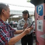 Petugas memantau pembayaran parkir nontunai oleh masyarakat di Kota Surabaya.
