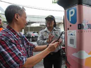 Petugas memantau pembayaran parkir nontunai oleh masyarakat di Kota Surabaya.